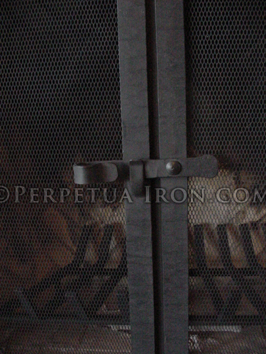 Detail of unembellished fireplace screen doors with textured steel frame with mesh fire screen.