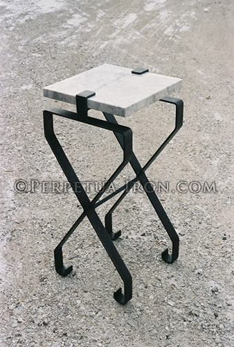 Forged steel table with stone slab top that is slid into a bracket holding it in place.