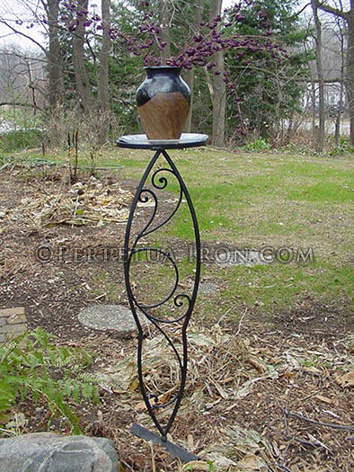 Decorative iron plant stand with scroll designs.