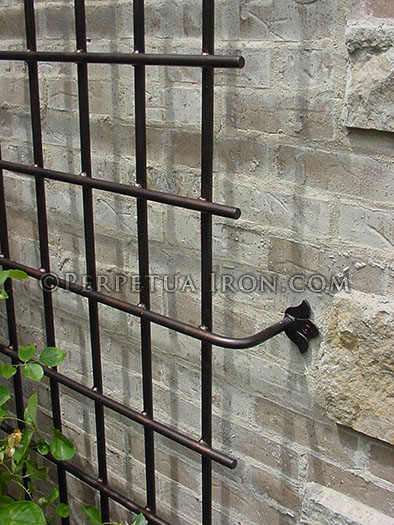 Detail of decorative iron trellis mounting point on a stone wall.
