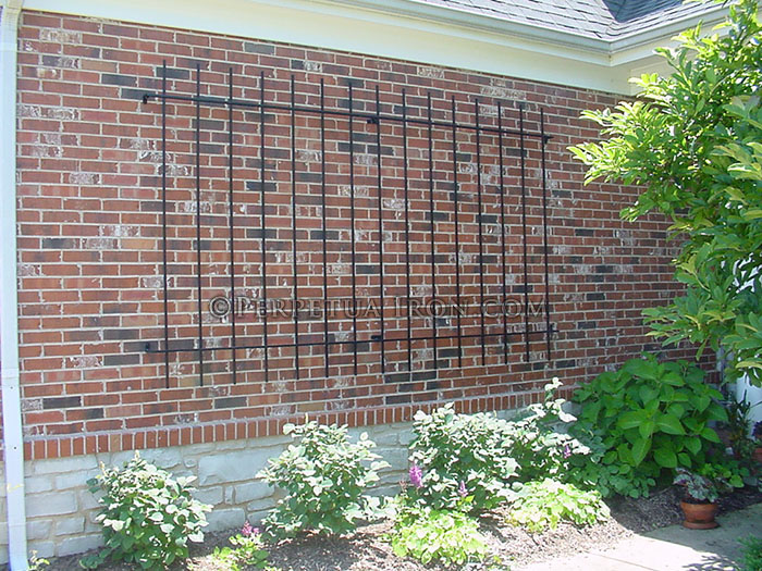 custom fabricated, simple, rectangular garden trellis mounted to a brick wall.