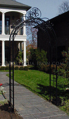 A black heavy duty decorative arched steel and iron trellis over a sidewalk