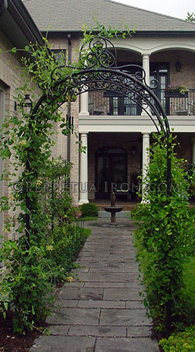 Heavy duty decorative arched steel and iron trellis over a sidewalk with plants growing up on both sides.