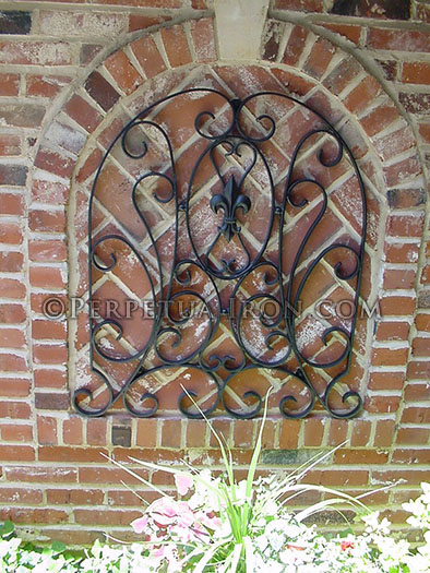 a wrought iron decorative panel that is formed to fit an arched brick wall detail