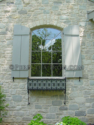 a wrought iron window box seen from a distance, showing the copmlete window above.
