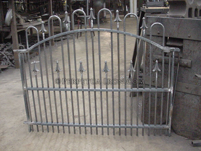 Uninstalled, shop image of a small iron gate for a garden with a loop and spear design Very tight bottom railing.