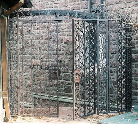 large ornate wrought iron gate by a stone structure.