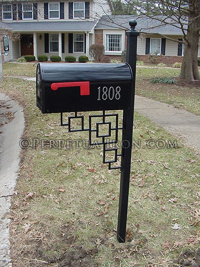 black mailbox in front of a house with a repeating square patterned finial