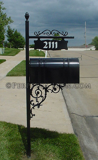 an ornamental iron mailbox post, with cast iron brackets for a sign that hangs over the box.