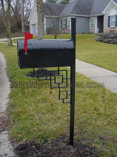 A mailbox post with cast iron finial and cast iron bracket.