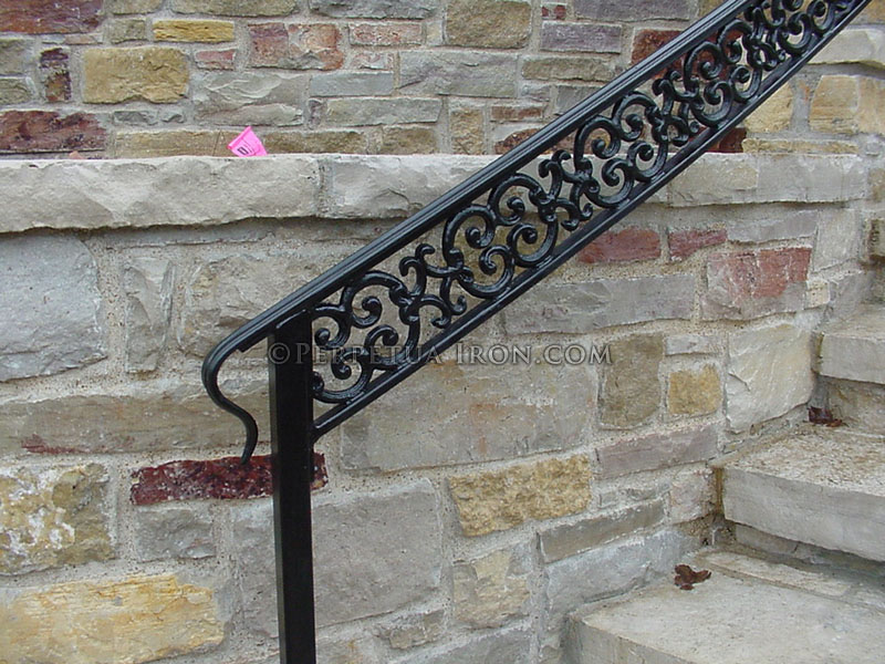 image of complex railing end against stone wall.